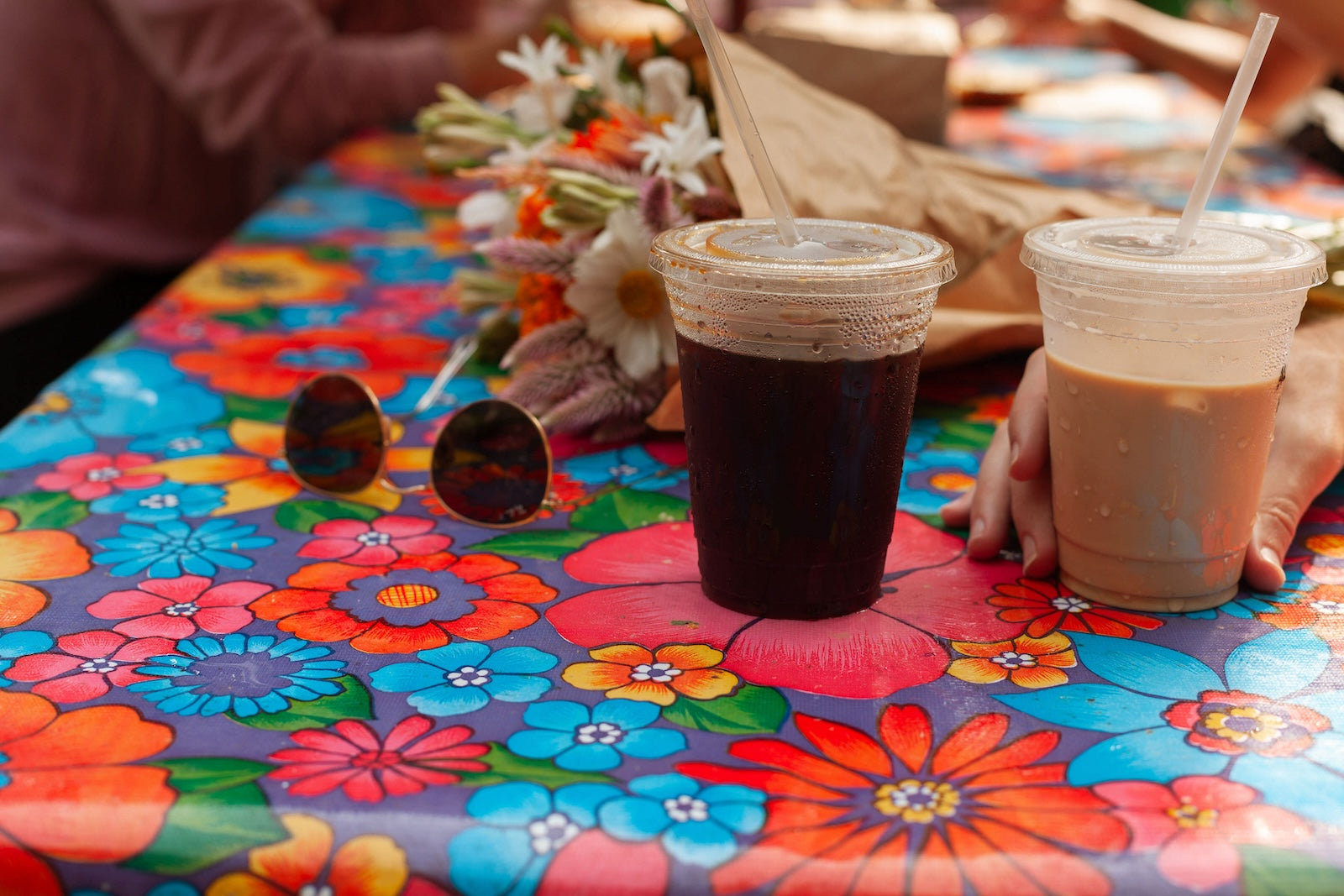 2 takeout coffees sitting on a colorful tablecloth to represent two business owners working together and whether or not to include a non-compete clause for independent contractors. 