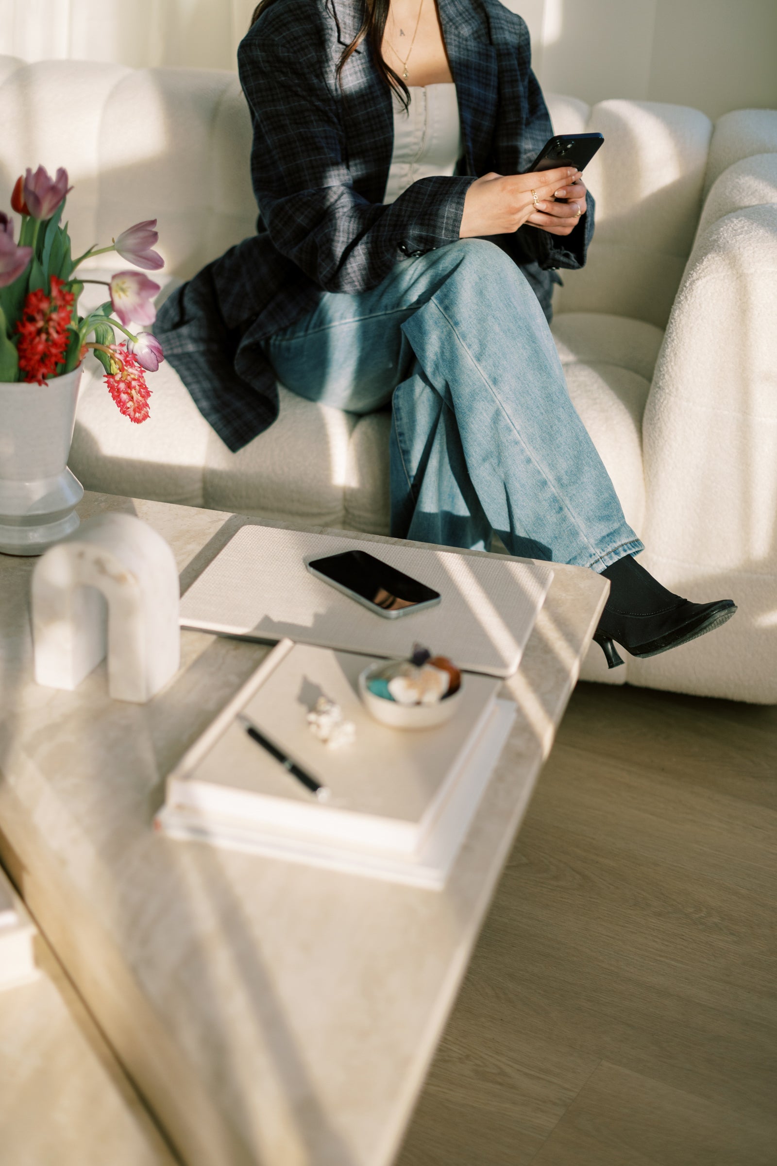 Casual attorney wearing jeans and plaid, typing on her phone and working to represent creatives in building and growing their brands with security.