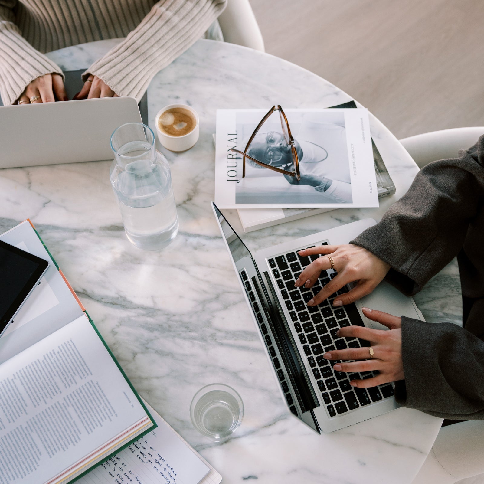 Two attorneys for creative entrepreneurs working at a desk in their office while drafting contract and legal templates for their clients and shop.